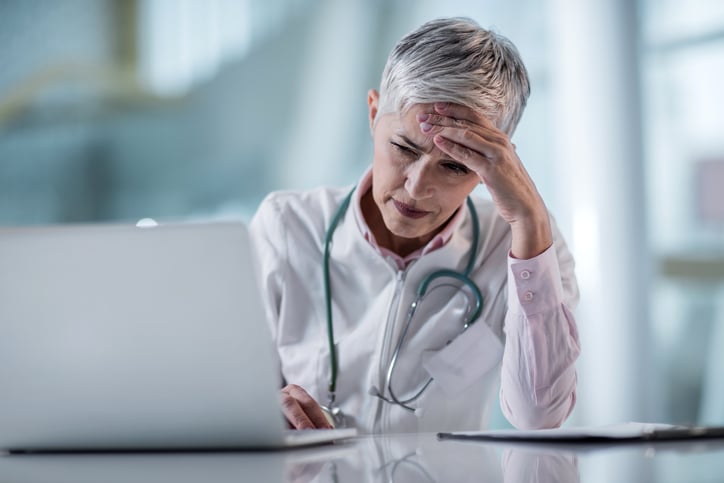 Female-physician-looking-at-laptop-and-stressed